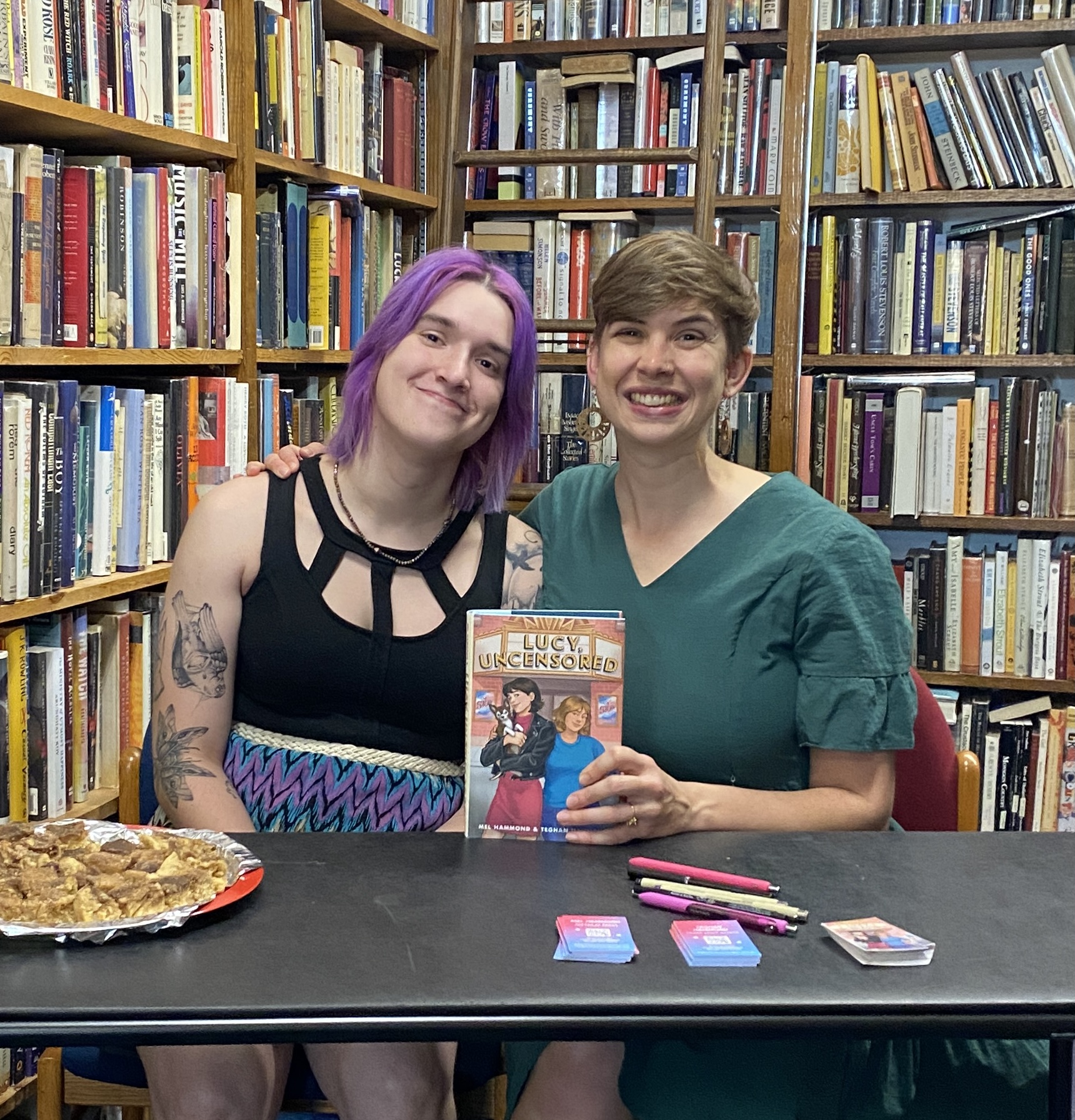 Mel and Teghan hold up Lucy, Uncensored in a book store