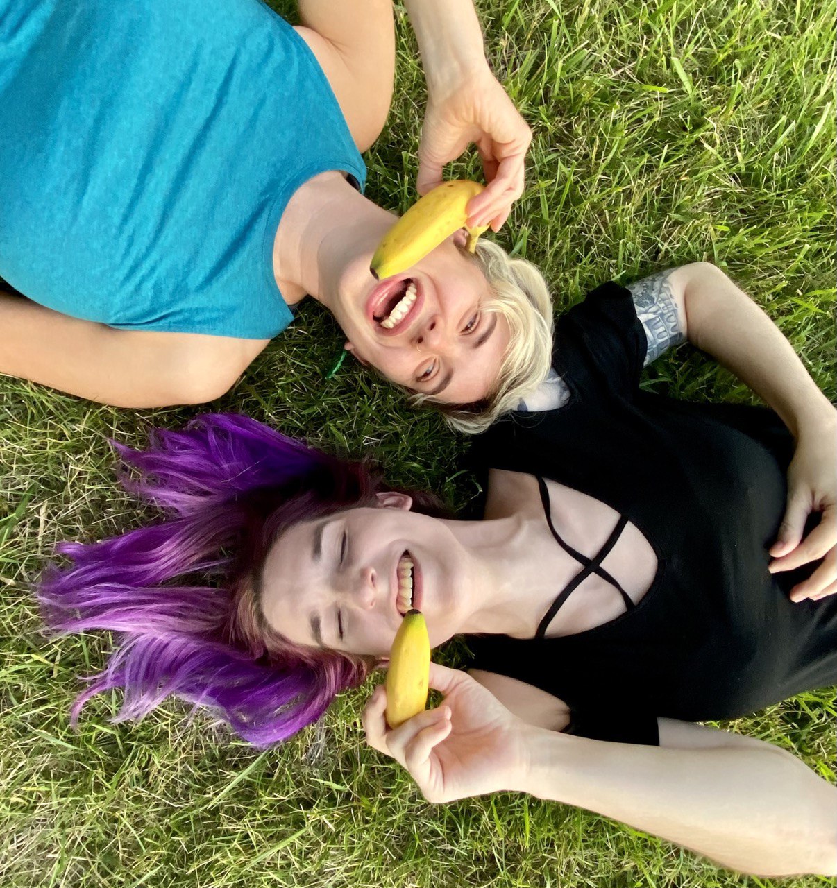 Teghan and Mel laugh in the grass while talking on banana phones